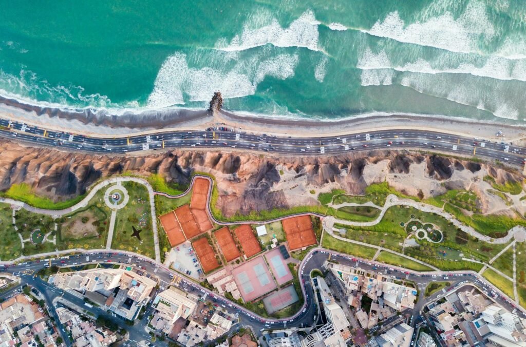 An ultra-realistic photo of a sunny day in Lima, Peru, with the Pacific Ocean in the background. In the foreground, a scenic boardwalk along the coastline, bustling with people enjoying the mild weather. The middle ground features a mix of modern high-rise buildings and historic colonial architecture, blending the old and new. The sky is filled with wispy, golden-hued clouds, casting a warm, inviting glow over the city. The scene captures the vibrant energy and unique blend of natural and urban elements that make Lima a captivating destination on the Pacific coast. photo of a sunny day in Lima, Peru, with the Pacific Ocean in the background. In the foreground, a scenic boardwalk along the coastline, bustling with people enjoying the mild weather. The middle ground features a mix of modern high-rise buildings and historic colonial architecture, blending the old and new. The sky is filled with wispy, golden-hued clouds, casting a warm, inviting glow over the city. The scene captures the vibrant energy and unique blend of natural and urban elements that make Lima a captivating destination on the Pacific coast.