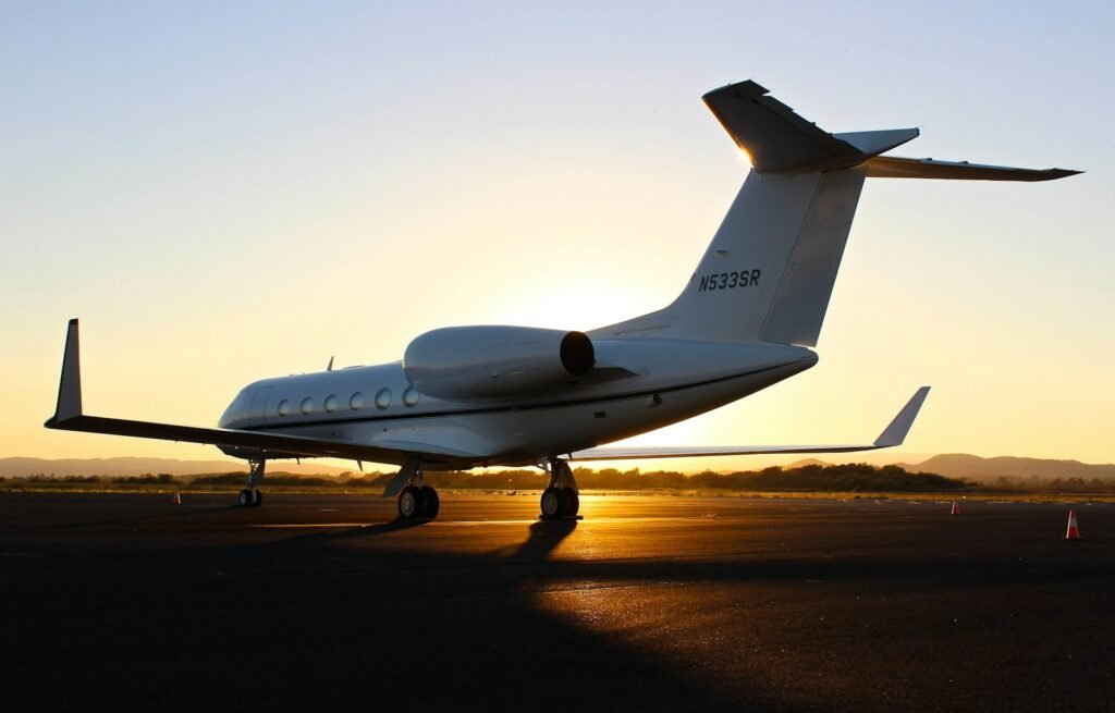 High-resolution, ultra-realistic photo of a private jet and a commercial airliner in the foreground, showcasing the key differences between charter flights and first-class travel. The private jet is sleek and modern, with a well-appointed interior visible through the windows. The commercial airliner is in the background, slightly blurred, representing the typical first-class experience. The scene is bathed in warm, golden lighting, creating a sense of luxury and exclusivity. The composition emphasizes the size and scale difference between the two aircraft, highlighting the more personalized and tailored nature of private air travel. High-resolution, ultra-realistic photo of a private jet and a commercial airliner in the foreground, showcasing the key differences between charter flights and first-class travel. The private jet is sleek and modern, with a well-appointed interior visible through the windows. The commercial airliner is in the background, slightly blurred, representing the typical first-class experience. The scene is bathed in warm, golden lighting, creating a sense of luxury and exclusivity. The composition emphasizes the size and scale difference between the two aircraft, highlighting the more personalized and tailored nature of private air travel.