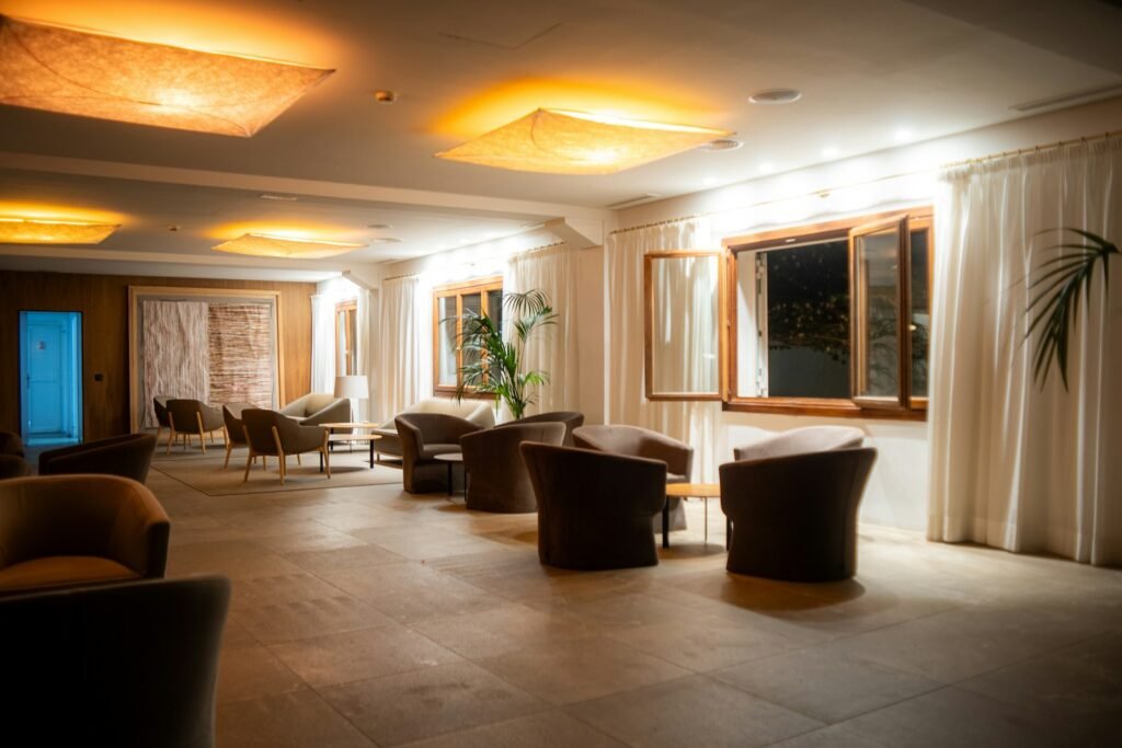 A high-resolution, hyper-realistic photographic scene depicting the contrast between the inviting ambiance of a cozy Manhattan boutique hotel and the imposing presence of a large upscale chain hotel in midtown. The boutique hotel features a warm, intimate lobby with plush furnishings, decorative lighting, and tasteful decor that evokes a sense of luxury and charm. In the background, the towering façade of the chain hotel stands in stark contrast, its sleek, modern design and uniform appearance conveying a more impersonal, corporate atmosphere. The scene is bathed in soft, natural lighting that highlights the distinctive qualities of each hotel type, inviting the viewer to compare and consider the pros and cons of each option. photographic scene depicting the contrast between the inviting ambiance of a cozy Manhattan boutique hotel and the imposing presence of a large upscale chain hotel in midtown. The boutique hotel features a warm, intimate lobby with plush furnishings, decorative lighting, and tasteful decor that evokes a sense of luxury and charm. In the background, the towering façade of the chain hotel stands in stark contrast, its sleek, modern design and uniform appearance conveying a more impersonal, corporate atmosphere. The scene is bathed in soft, natural lighting that highlights the distinctive qualities of each hotel type, inviting the viewer to compare and consider the pros and cons of each option.