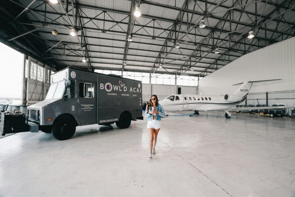 An elegant private jet sits on a tarmac, its sleek fuselage gleaming in the warm afternoon sun. In the foreground, a well-dressed traveler confidently strides towards the aircraft, effortlessly navigating their way with a stylish carry-on bag in hand. The scene is one of seamless accessibility, where every detail has been carefully considered to cater to the unique needs and preferences of the discerning passenger. The lighting is soft and natural, casting a subtle glow that highlights the aircraft's premium finishes and the passenger's relaxed demeanor. In the background, a team of attentive ground staff stands ready to assist with any special accommodations or oversized baggage, ensuring a truly personalized and hassle-free travel experience. High-resolution, ultra-realistic photo of a private jet and a commercial airliner in the foreground, showcasing the key differences between charter flights and first-class travel. The private jet is sleek and modern, with a well-appointed interior visible through the windows. The commercial airliner is in the background, slightly blurred, representing the typical first-class experience. The scene is bathed in warm, golden lighting, creating a sense of luxury and exclusivity. The composition emphasizes the size and scale difference between the two aircraft, highlighting the more personalized and tailored nature of private air travel.