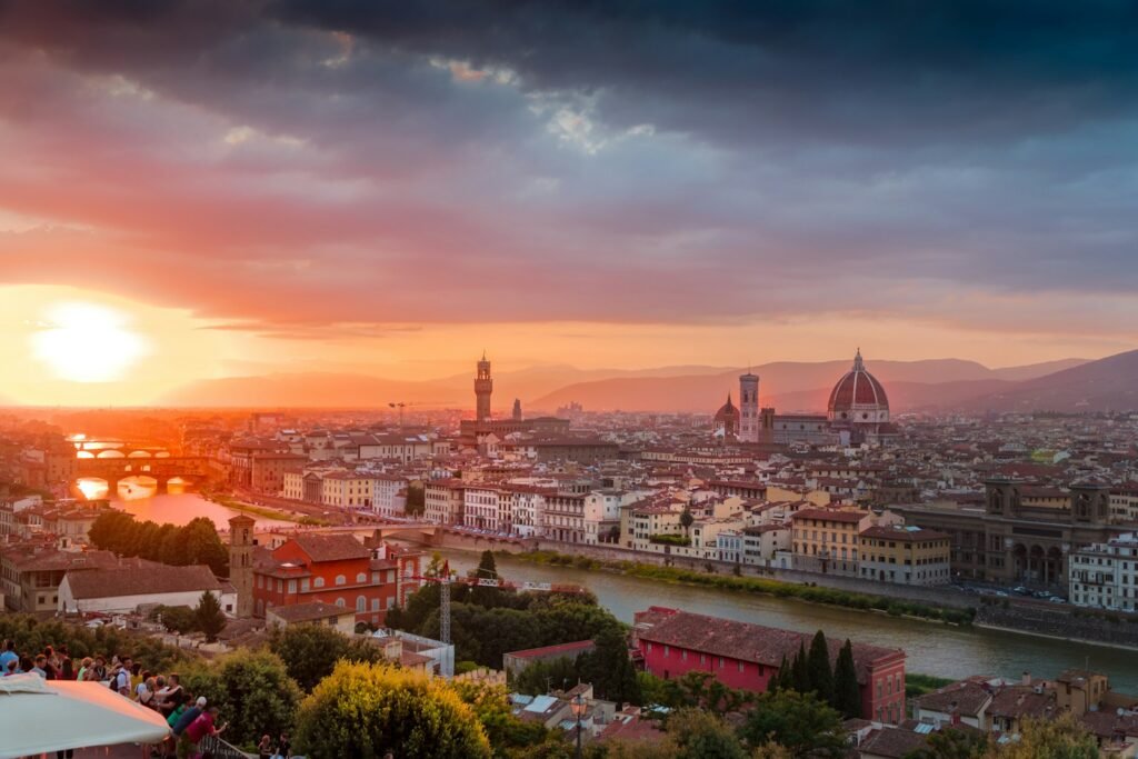 A sun-soaked Renaissance cityscape of Florence, Italy. In the foreground, the iconic Duomo cathedral rises majestically, its striking domed roofline and intricate marble facades glimmering in the warm light. Surrounding the cathedral, a sprawling network of cobblestone streets and alleyways, lined with charming historic buildings, artisan shops, and quaint cafes. In the middle ground, the serene Arno River flows peacefully, its banks dotted with pedestrians and horse-drawn carriages. In the distance, the rolling Tuscan hills provide a stunning backdrop, bathed in a soft golden glow. The scene exudes a timeless, old-world atmosphere, inviting the viewer to immerse themselves in the rich cultural heritage and enchanting ambiance of this Renaissance gem. Istanbul city scape Florence Italy one of the best cities in europe to visit