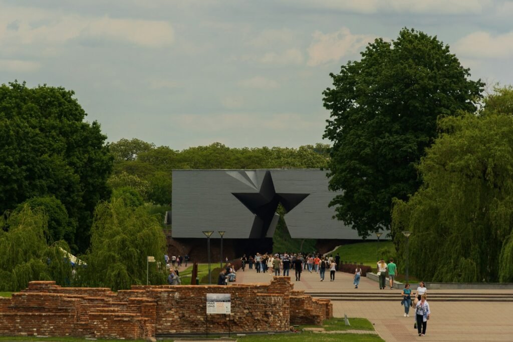 A grand European landscape stretching before the viewer, dotted with historic landmarks and memorials. In the foreground, a tour group stands in reverence, gazing upon the solemn reminders of World War II's battles and sacrifices. The scene evokes a sense of contemplation and respect, inviting the viewer to embark on an emotional journey through Europe's wartime history.
