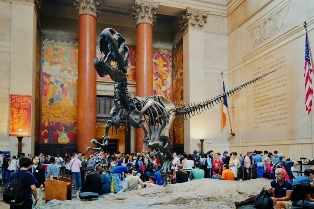 In the foreground, a group of curious adults and children exploring the grand entryways of renowned New York City museums, their faces alight with wonder and excitement. The scene is bathed in warm, golden-hour lighting, creating a sense of adventure and discovery. The museums' facades are detailed with intricate architectural elements, drawing the eye inward. A sense of exploration and learning permeates the image, capturing the essence of must-see institutions for inquisitive young minds in the heart of the Big Apple.