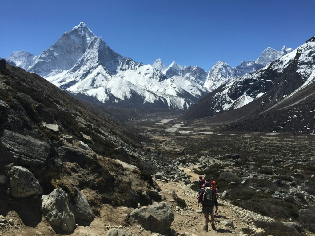 A stunning vista of the majestic Himalayan mountains in Nepal, captured with a wide-angle lens to showcase the towering peaks and rugged terrain. In the foreground, a trekker navigates a winding mountain path, dwarfed by the awe-inspiring landscape. The warm, golden light of the setting sun casts a soft glow over the scene, creating a serene and tranquil atmosphere. Wisps of clouds drift lazily across the sky, adding depth and dimension to the image. The overall impression is one of adventure, natural wonder, and the sheer scale of the Himalayan range, all within a budget-friendly destination.