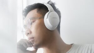 A man wearing a white headphone in a airplane, which is one of the best noise canceling headphones for Flights.