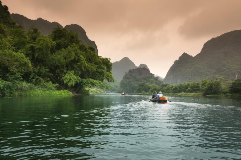 Travelers exploring the Peru Amazon River by boat surrounded by lush rainforest and misty mountains during an adventure tour.