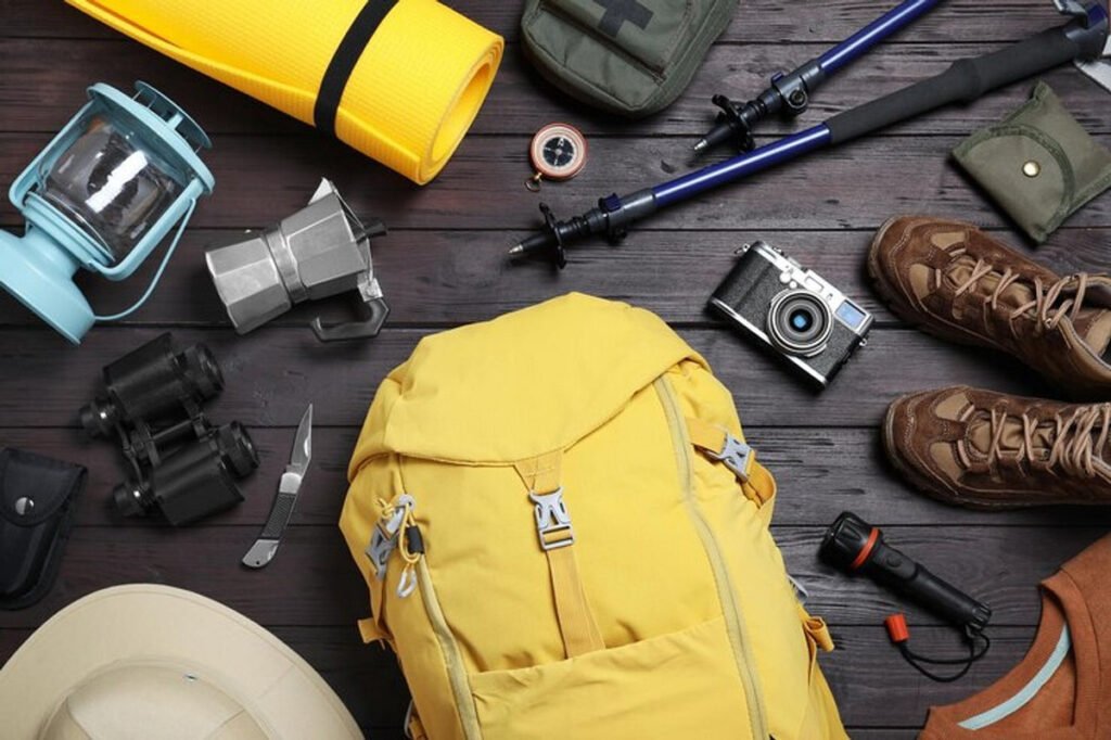 Flat lay of essential travel safety gear including a yellow backpack, first aid kit, flashlight, hiking boots, and camera—perfect for safe and organized travel.